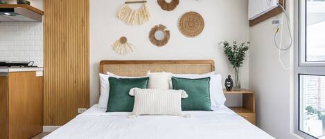 A modern bedroom with a large bed, wooden headboard, and decorative wall hangings.
