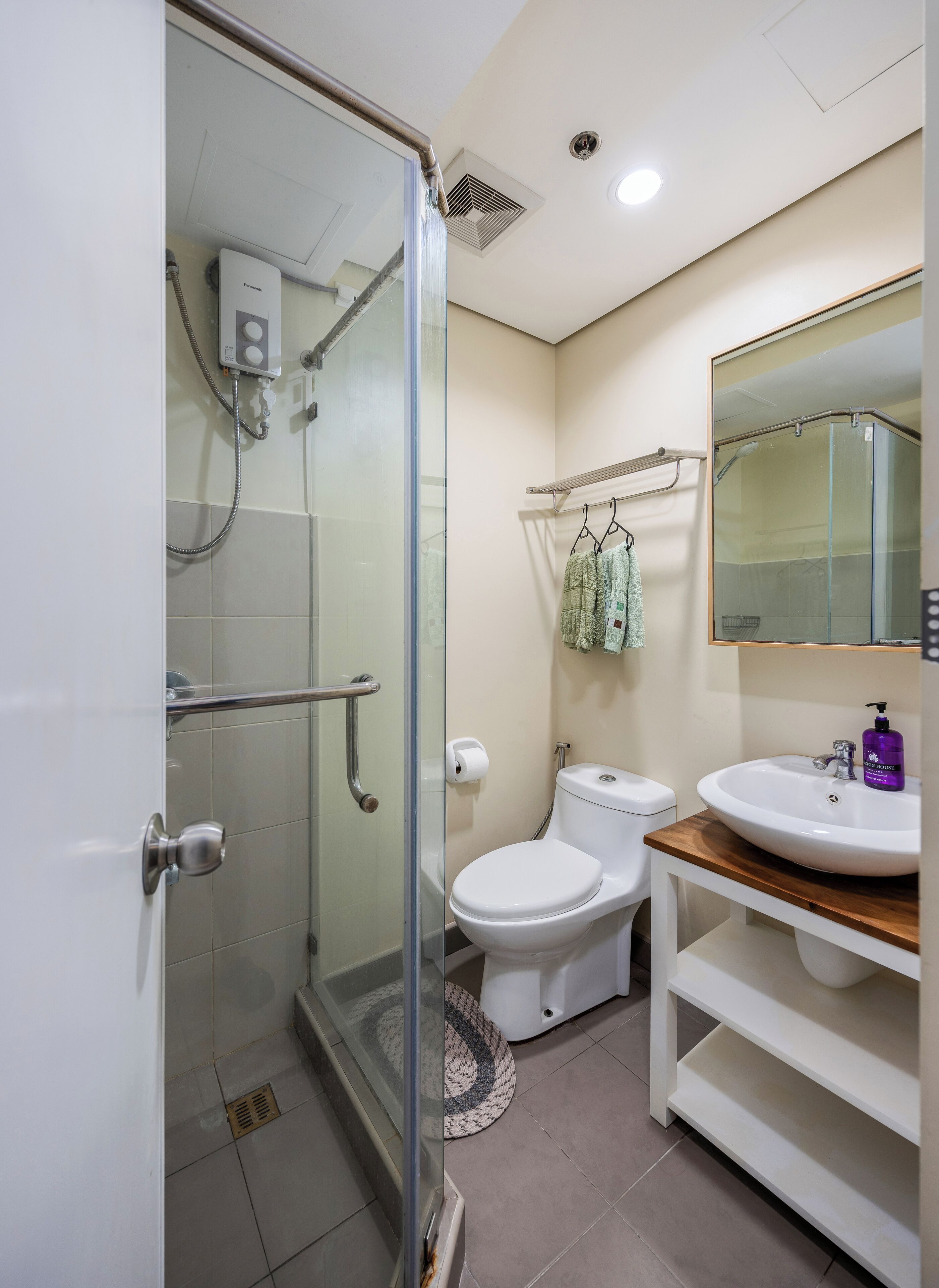 A modern bathroom with a glass shower enclosure, a white toilet, and a sink with a wooden countertop.