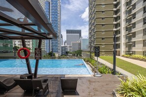 A rooftop pool with lounge chairs, surrounded by high-rise buildings. - Avida Riala IT Park - Virgo Nest Rentals (Apas)
