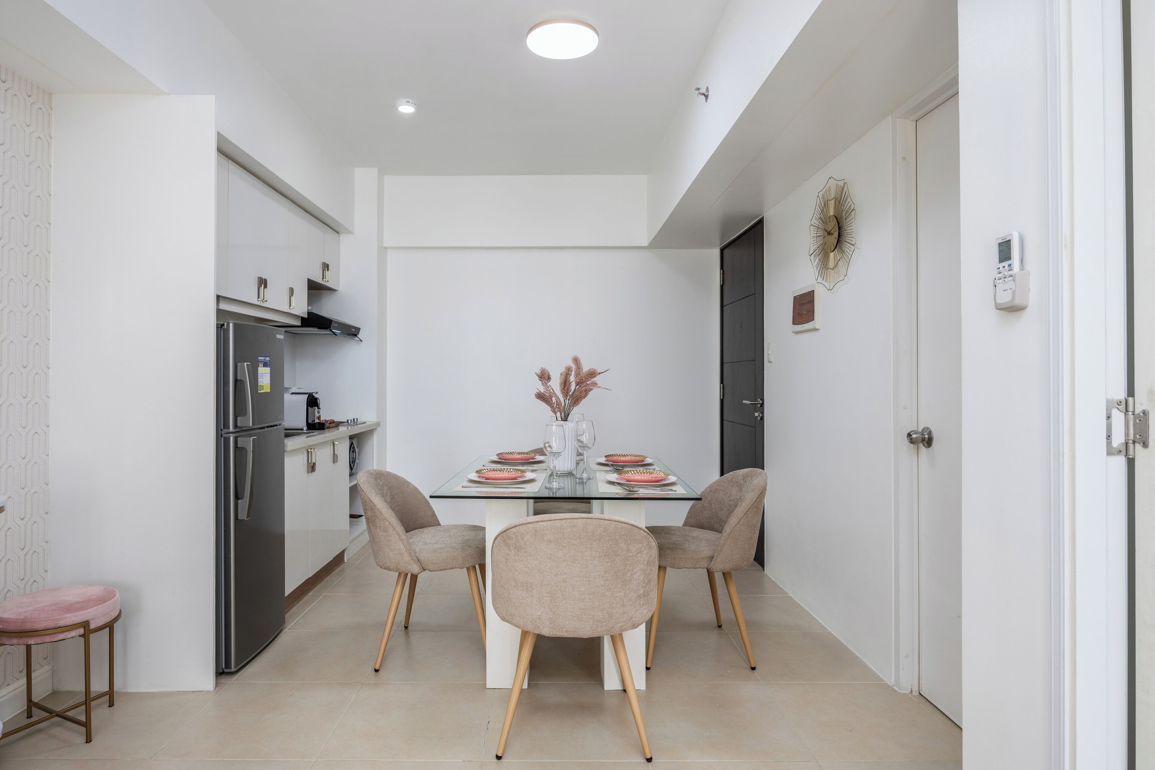 A modern kitchen with a dining table set for four, a refrigerator, and a decorative vase on the table.