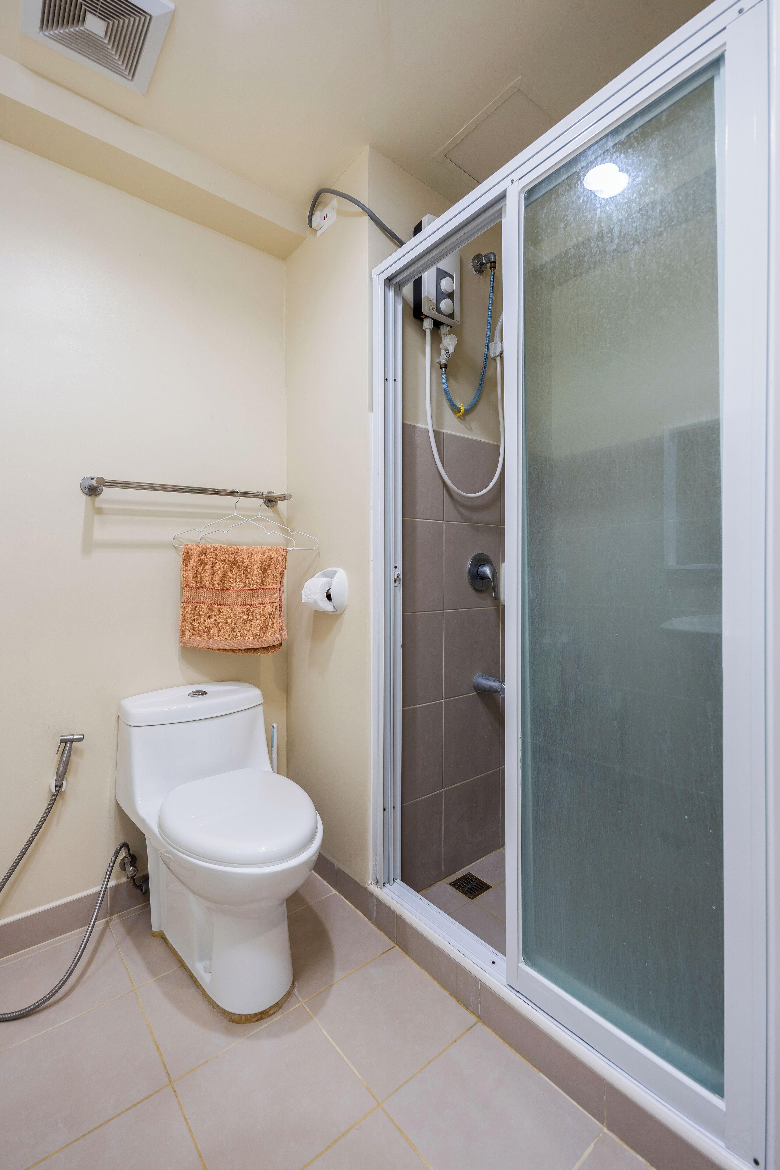 Une salle de bain comprenant des toilettes, une douche à parois de verre et un porte-serviettes.