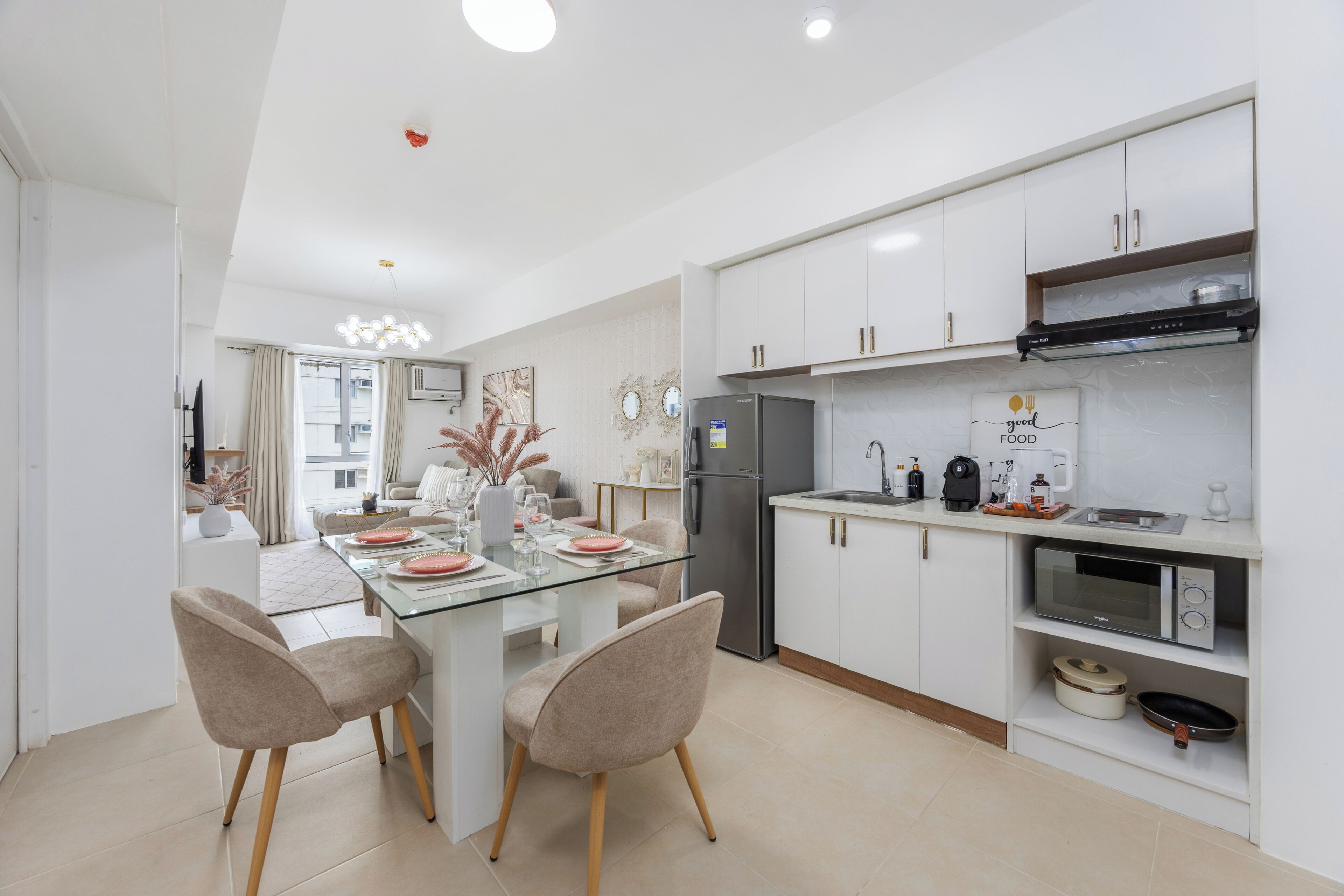 A modern kitchen with white cabinetry, a central island with chairs, a microwave, and a refrigerator.