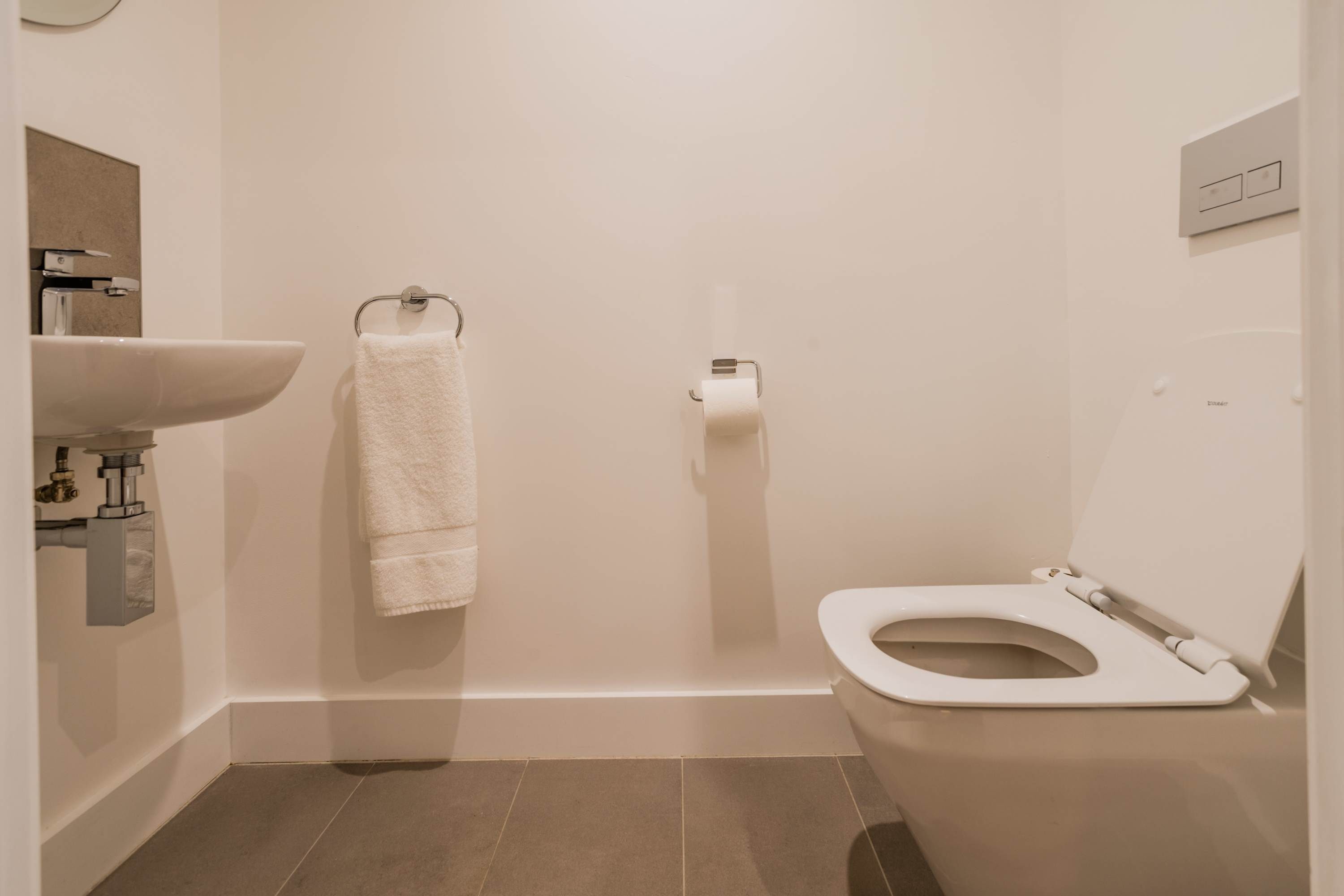 Une petite salle de bain moderne, équipée de toilettes, d’un lavabo et d’un porte-serviettes.
