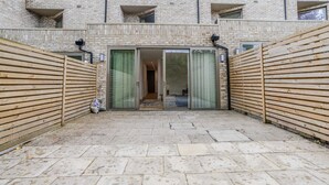 A courtyard with a brick building, a wooden fence, and a tiled floor.