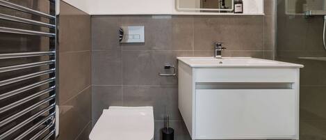 A modern bathroom with a toilet, sink, and shower.