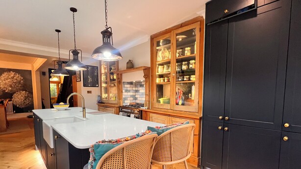 A modern kitchen with a central island, bar stools, pendant lighting, and dark cabinetry. - Home in Appledore with own parking and Hot Tub. Dogs welcomed (Appledore)