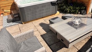 A hot tub with a wooden deck, outdoor seating, and a table with a candle. - Home in Appledore with own parking and Hot Tub. Dogs welcomed (Appledore)