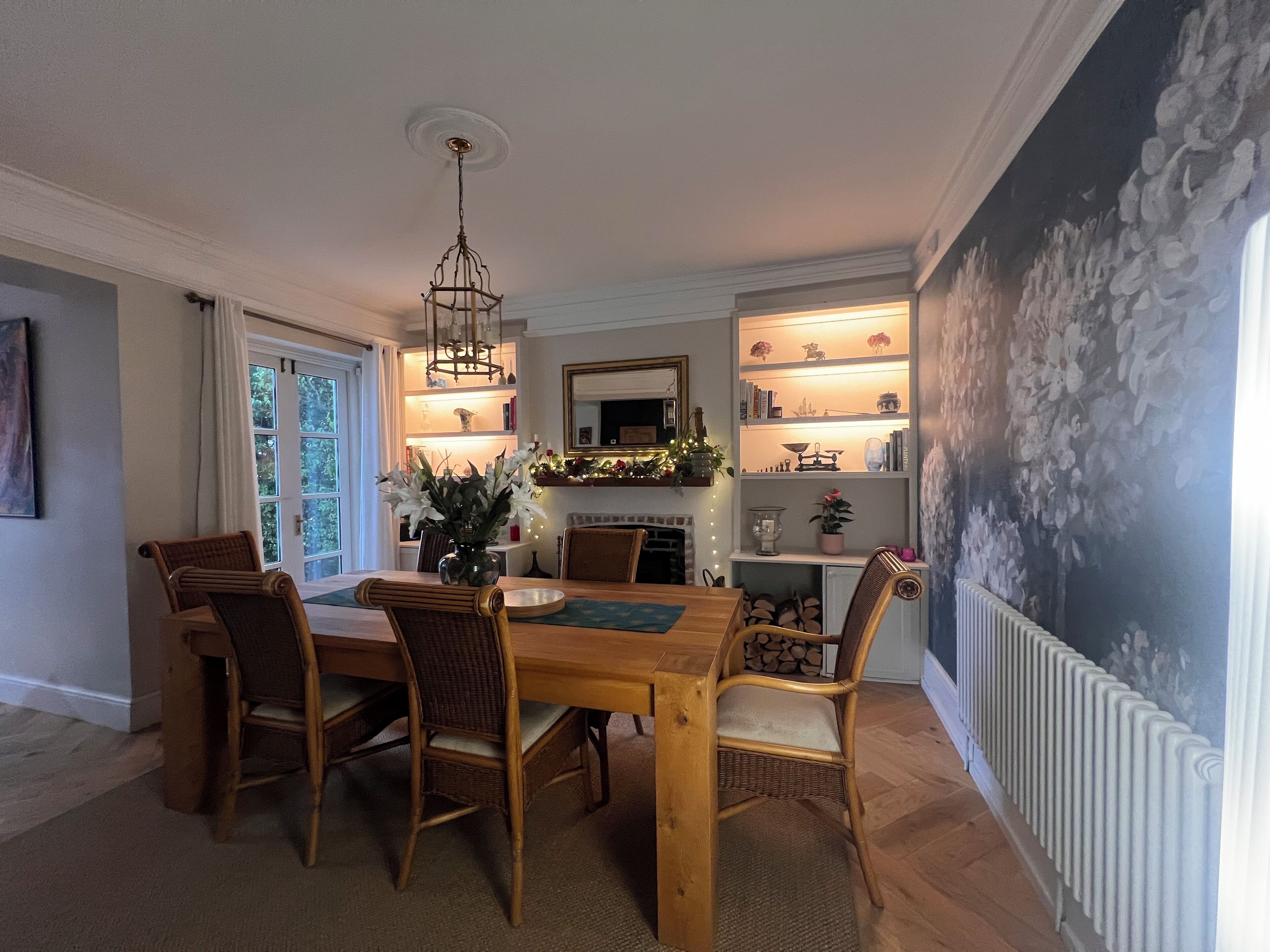 Een eetkamer met een houten tafel en stoelen, een kroonluchter en een open haard.