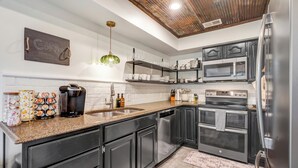 Una cocina moderna con armarios oscuros, electrodomésticos de acero inoxidable y un letrero de pizarra.