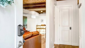 Una puerta con cerradura y manija, una pared blanca y un techo de madera.