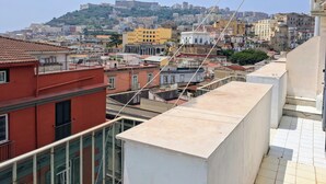 Un paisaje urbano que combina edificios modernos e históricos, incluyendo un edificio amarillo destacado y una construcción fortificada en una colina.