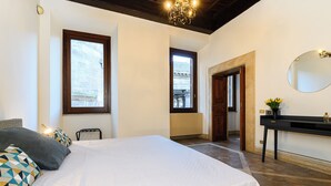 A bedroom with a large bed, a nightstand, a mirror, and a window.