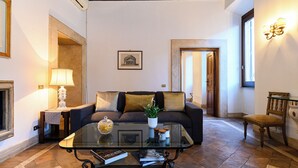 A living room with a sofa, a glass coffee table, a lamp, and a framed picture on the wall.