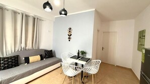 A modern living room with a sofa, white chairs, a dining table, and a ceiling light fixture. - Casa Damour  (Sidari)