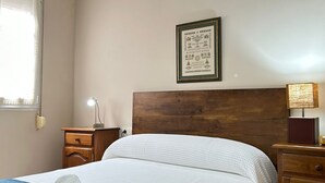 A neatly made bed with a headboard, a bedside lamp, a nightstand, and a framed picture on the wall. - Cariño BBQ House - Casa Senen (Cariño)