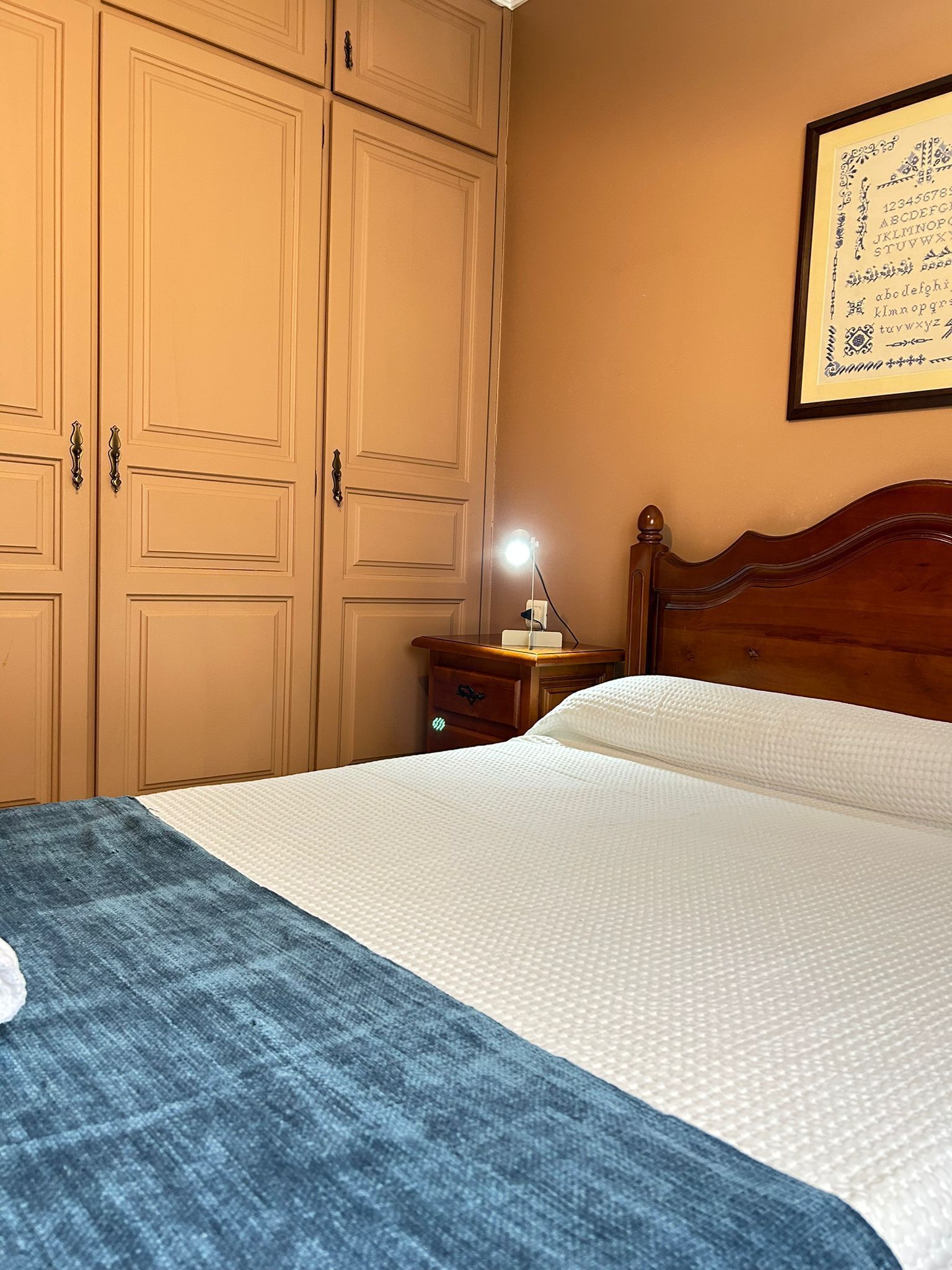 Une chambre à coucher avec un lit, une table de chevet, une lampe et une armoire.