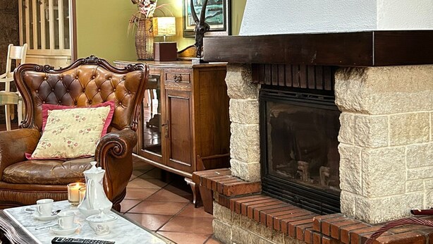 A cozy living room with a fireplace, a leather sofa, a coffee table, and a cabinet. - Cariño BBQ House - Casa Senen (Cariño)