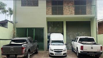 Tres vehículos estacionados frente a un edificio con fachada verde y una puerta de garaje.