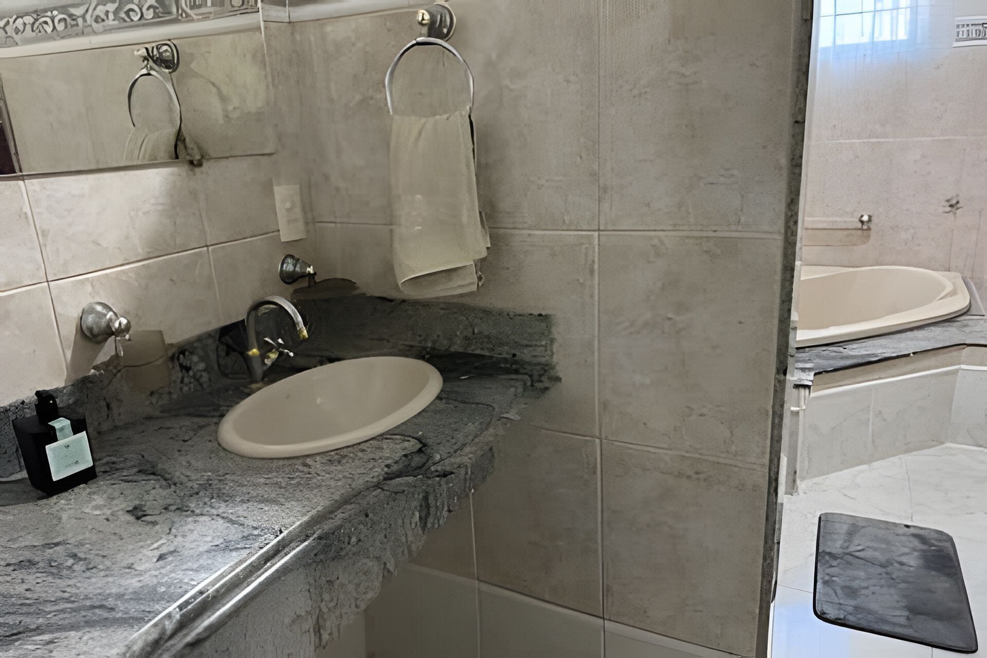 A bathroom with a marble sink, a towel rack, and a bathtub.