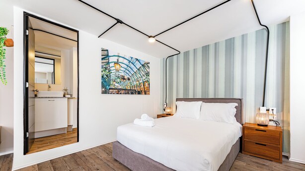 A modern bedroom with a large bed, a nightstand, a mirror, and a painting on the wall. - VH | Condesa nice loft with roof terrace + GYMNASIUM | 248 (Ciudad de México)
