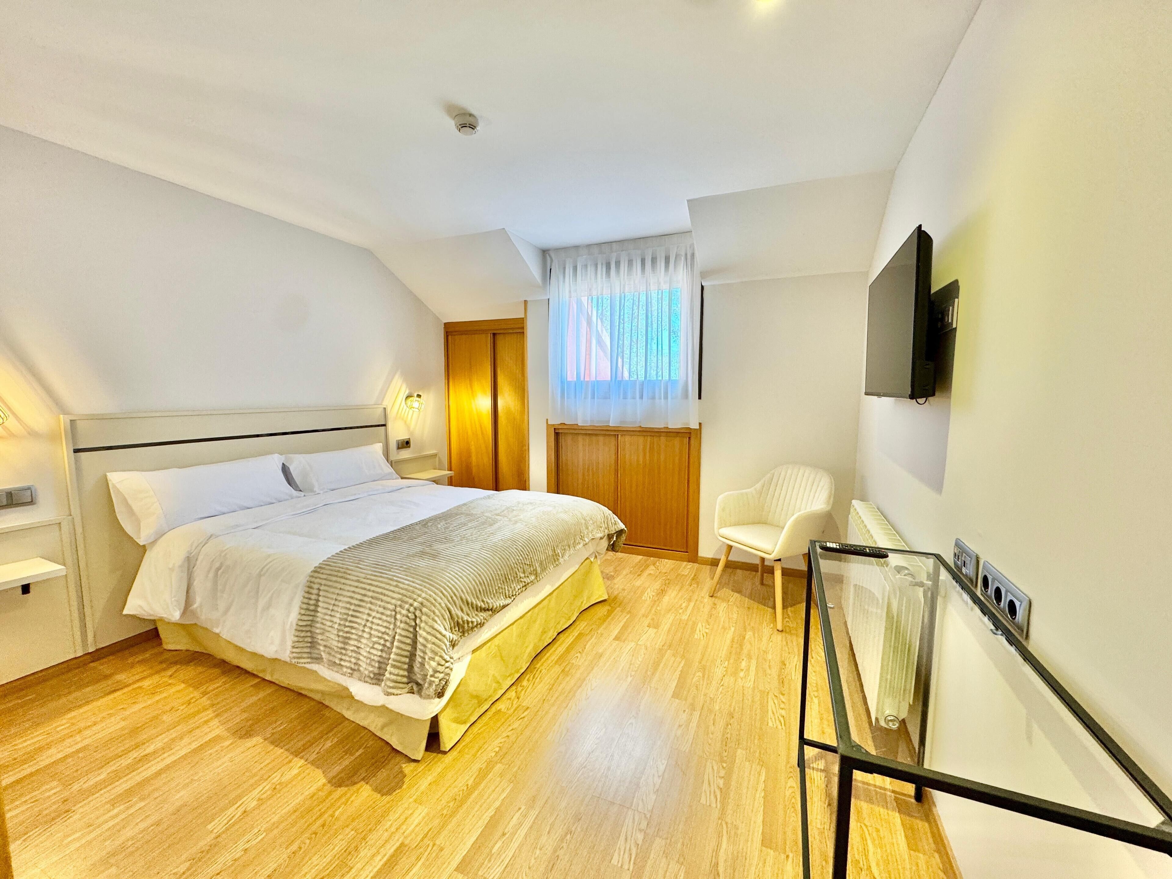 Un dormitorio con cama, una silla, un televisor y un radiador.