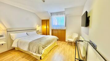 A bedroom with a bed, a chair, a TV, and a radiator.