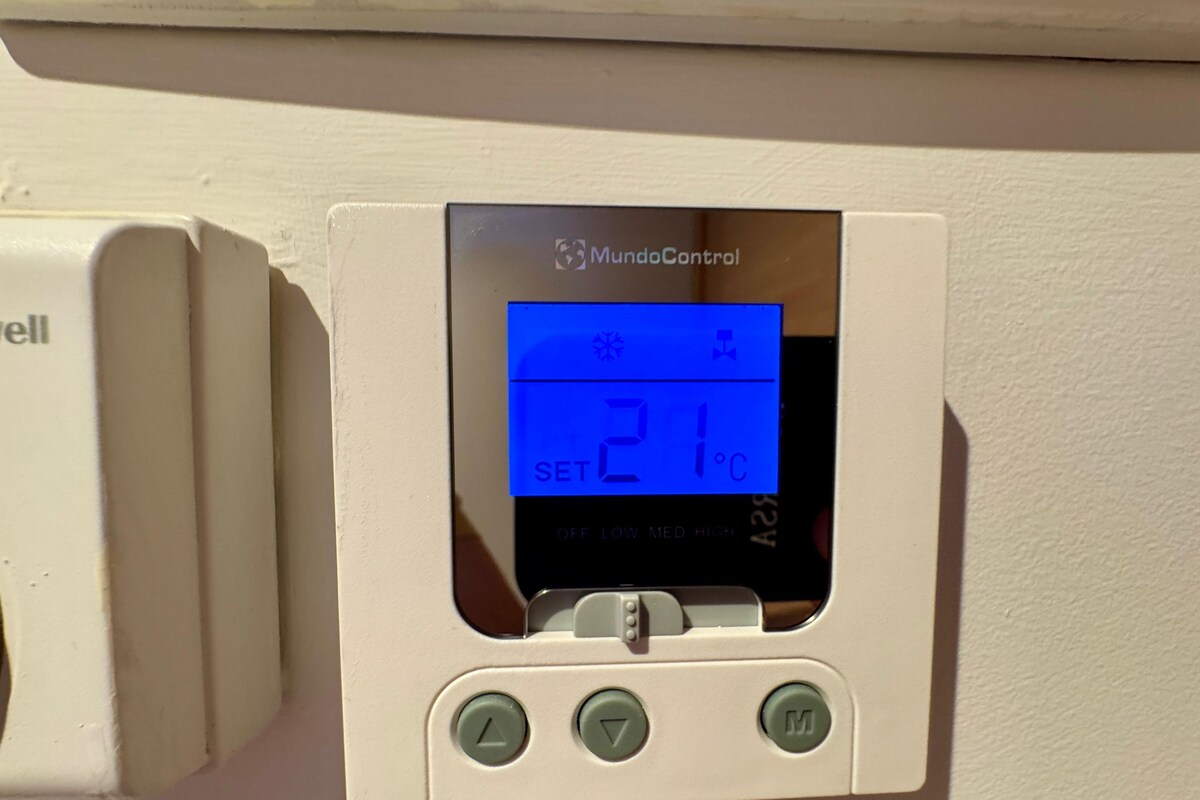 Un termostato digital con pantalla que muestra 21°C, configurado en BAJO, MEDIO y ALTO.