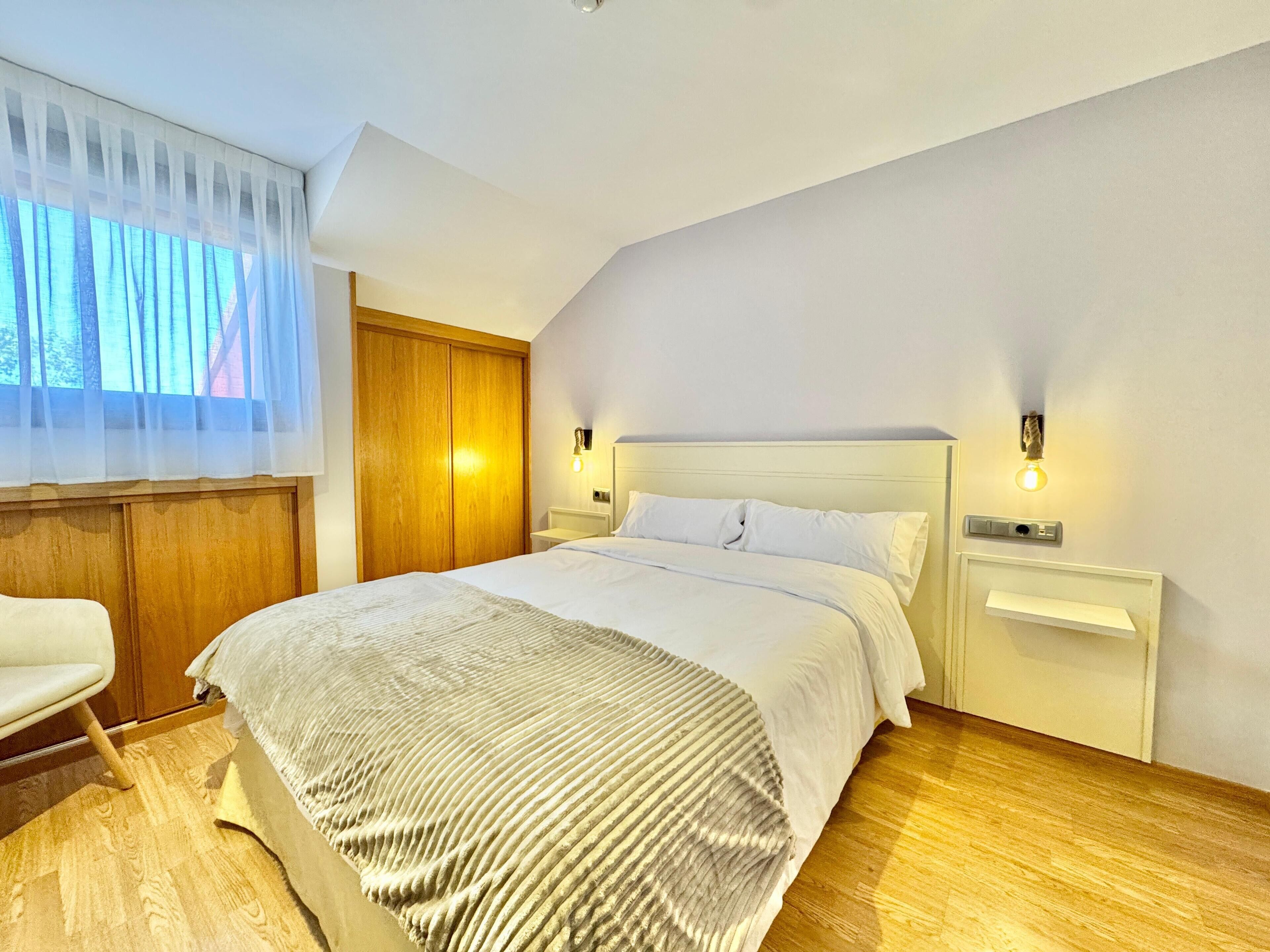A modern bedroom with a large bed, wooden wardrobe, and a chair.