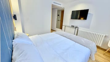 Una habitación de hotel moderna con una cama grande, un televisor de pantalla plana en la pared y un radiador.