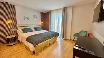 Habitación de hotel con cama, escritorio, silla y televisor.