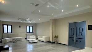 A modern hotel lobby with a seating area, a reception desk, and a large door labeled "DIRÓ HOTEL". - Hotel Diró (Avila)