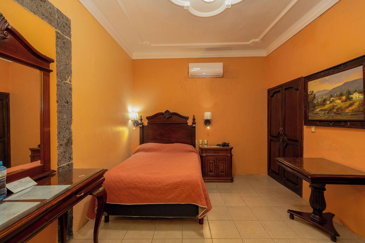 Une chambre d’hôtel avec un lit, une table de chevet, une lampe et un tableau au mur.