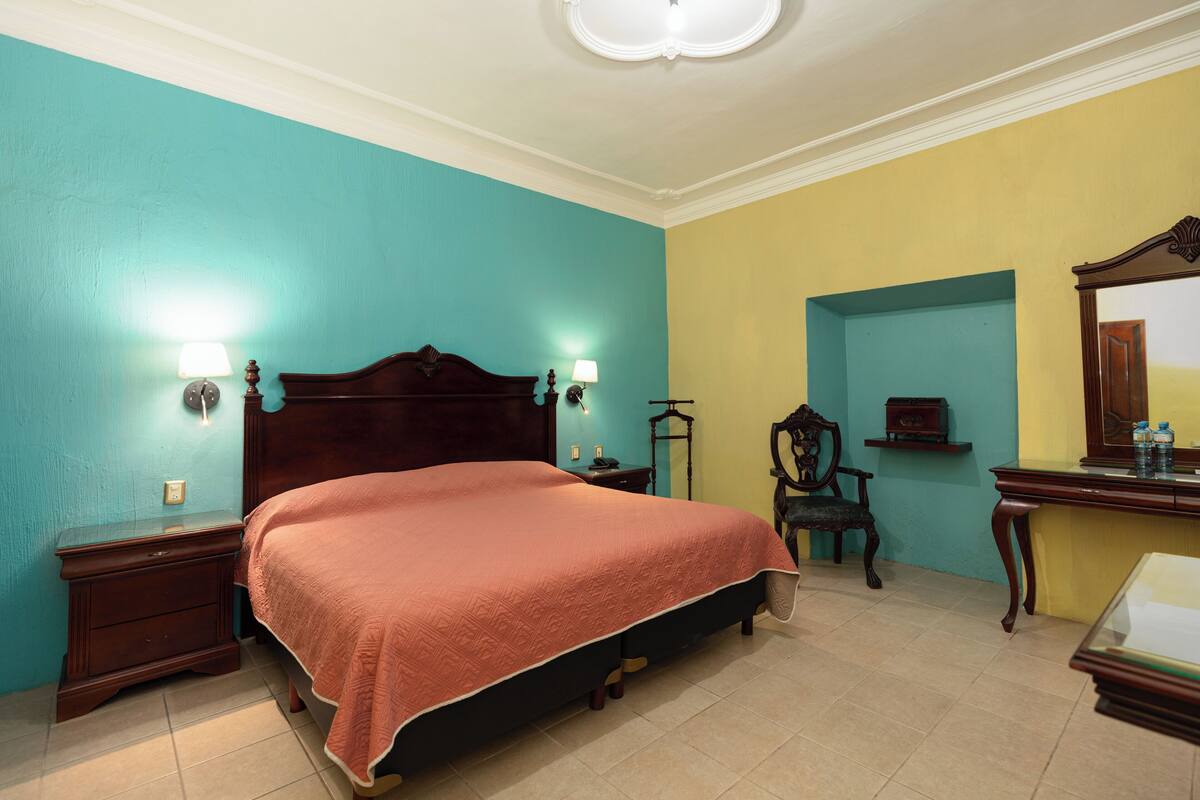 Une chambre à coucher comprenant un lit, des tables de chevet, une commode et une chaise.