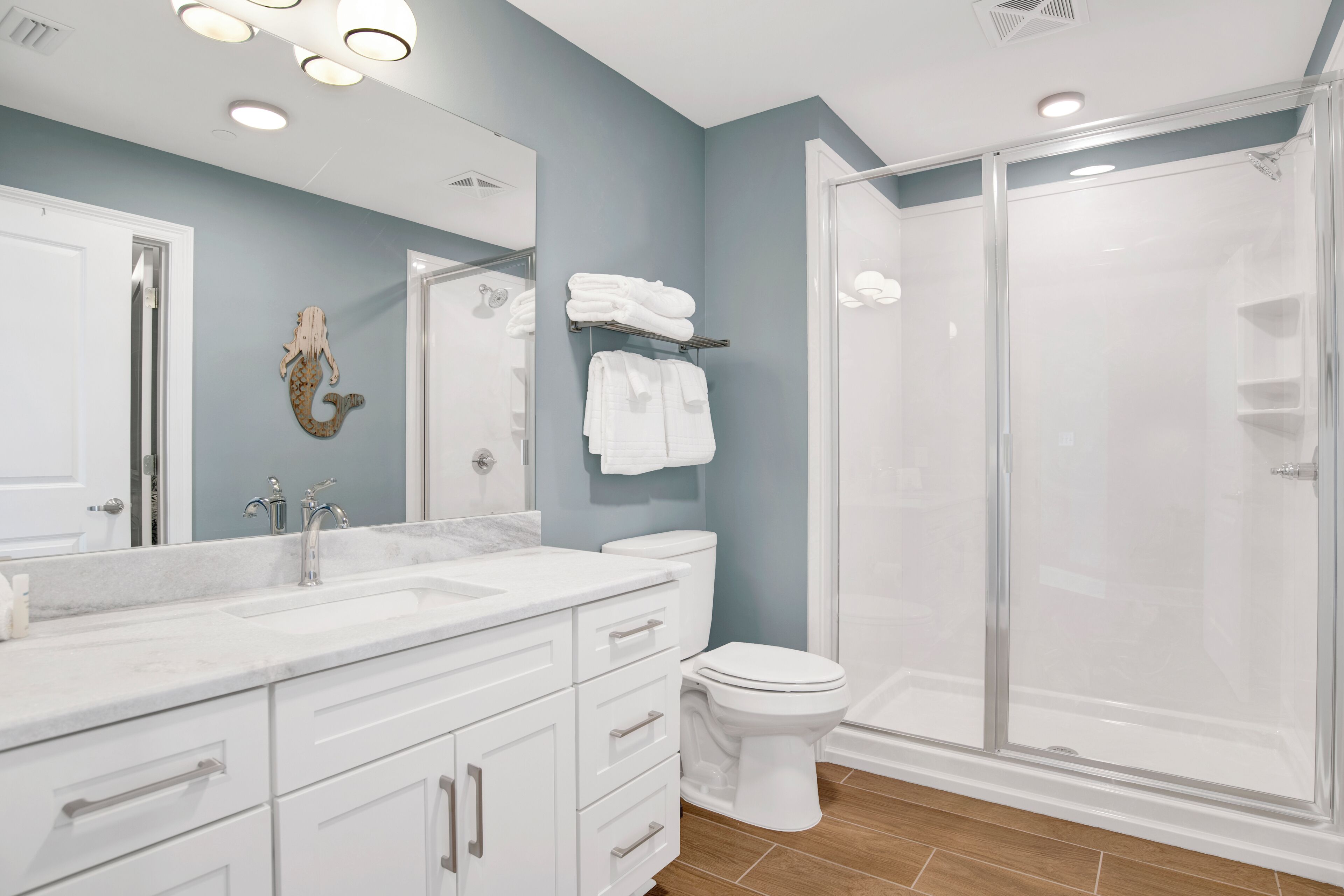 A modern bathroom with a marble vanity, a glass shower enclosure, and a toilet.