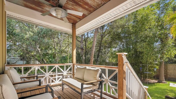 Un espace extérieur abrité, doté de mobilier en bois et d’un ventilateur de plafond.