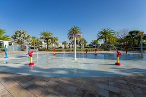 A water play area with multiple water jets and a central fountain, surrounded by palm trees and a clear sky. - Premium Architecture | 3 Masters | 15 Min Disney (Kissimmee)