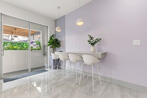 A modern kitchen with a glass door leading to a balcony, white bar stools, and pendant lighting. - Premium Architecture | 3 Masters | 15 Min Disney (Kissimmee)