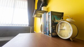Una mesa de madera con un despertador blanco y libros titulados 'A Holiday to Die For' y 'James Patterson'.