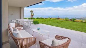 A patio with wicker furniture, a table, and a view of the sea. - Villa Melodia - Scopello (Scopello)