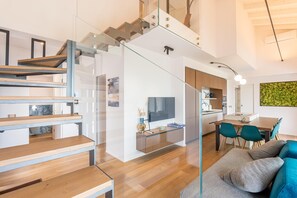 Un intérieur moderne comprenant un escalier, un coin repas et un espace de vie avec un canapé.