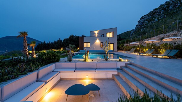 A modern house with a swimming pool, outdoor seating, and a view of a mountain. - Villa Melodia - Scopello (Scopello)