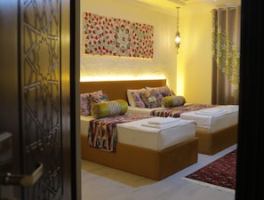 A hotel room with two beds, a patterned wall hanging, a hanging light fixture, and a patterned curtain. - Oasis al Khiva Boutique Hotel Inside Citadel (Khiva)