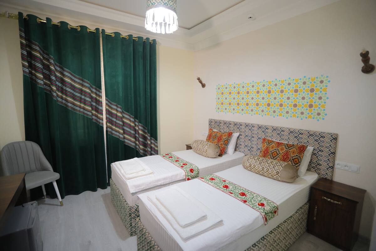 A hotel room with two beds, a desk, a chair, and a wardrobe.