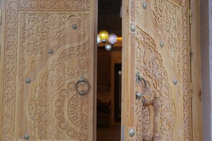 A wooden door with intricate carvings and a brass handle. - Oasis al Khiva Boutique Hotel Inside Citadel (Khiva)