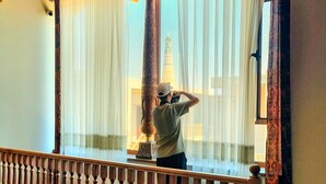 A person standing on a balcony with a view of a tower through sheer curtains. - Oasis al Khiva Boutique Hotel Inside Citadel (Khiva)