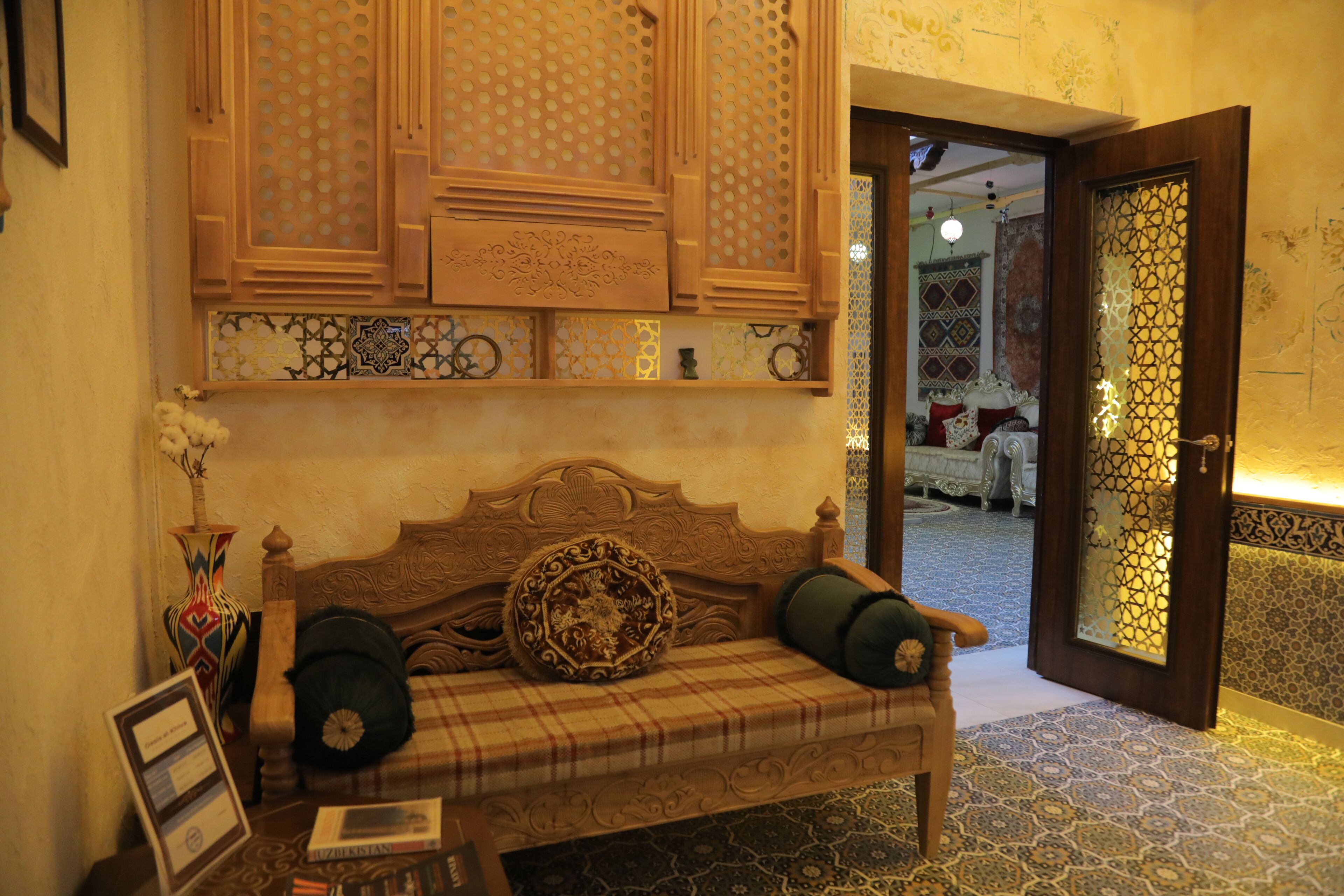 A traditional room with a wooden bench, patterned tiles, and a decorative door.