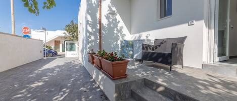 A residential property with a paved driveway, a stop sign, a gate, and a small patio with steps leading to a door.