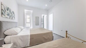 Une chambre à coucher comprenant un lit, une table de chevet, un miroir et une porte donnant sur une salle de bain.