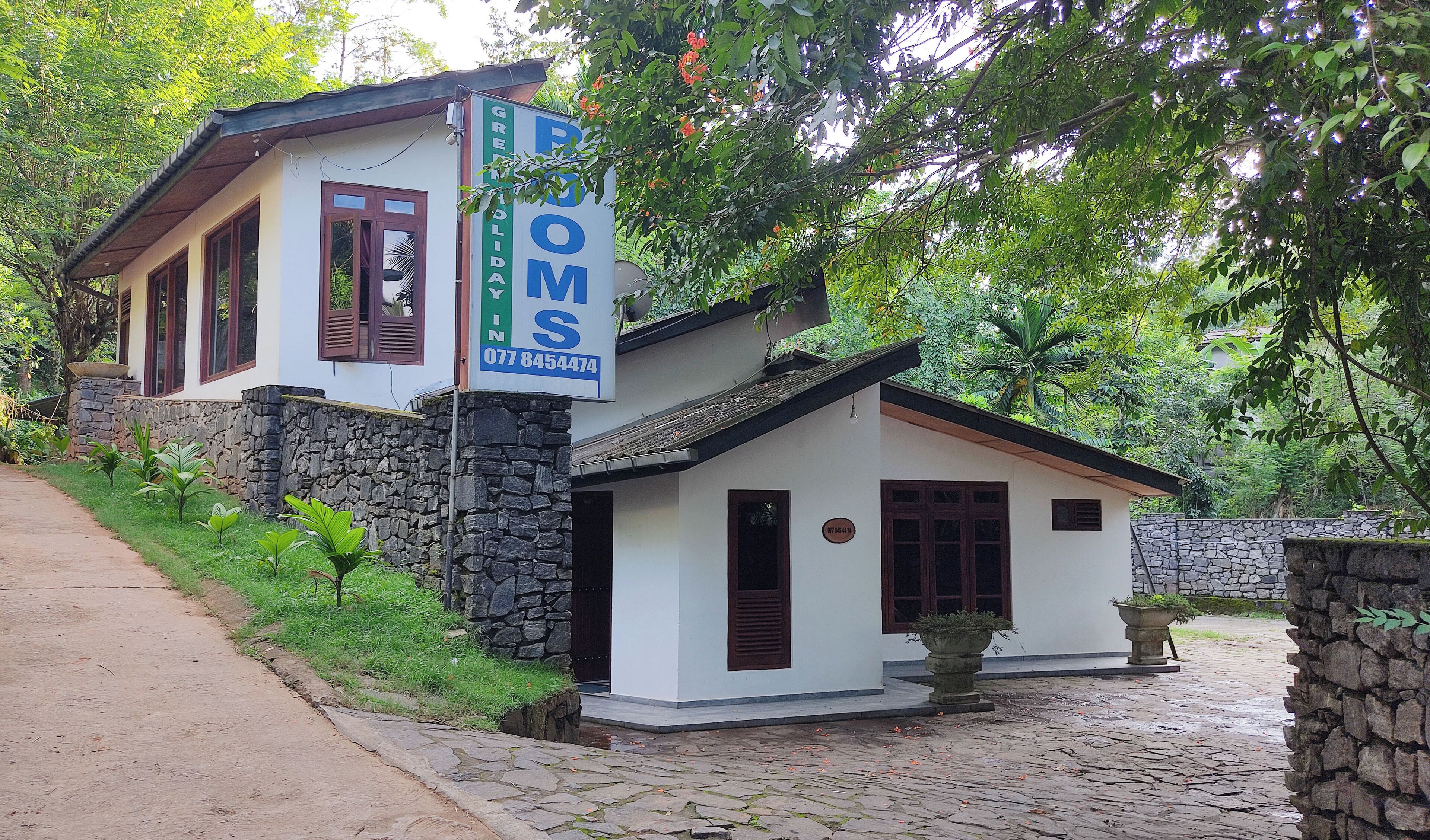 A two-story house with a stone facade and a signboard advertising a business.