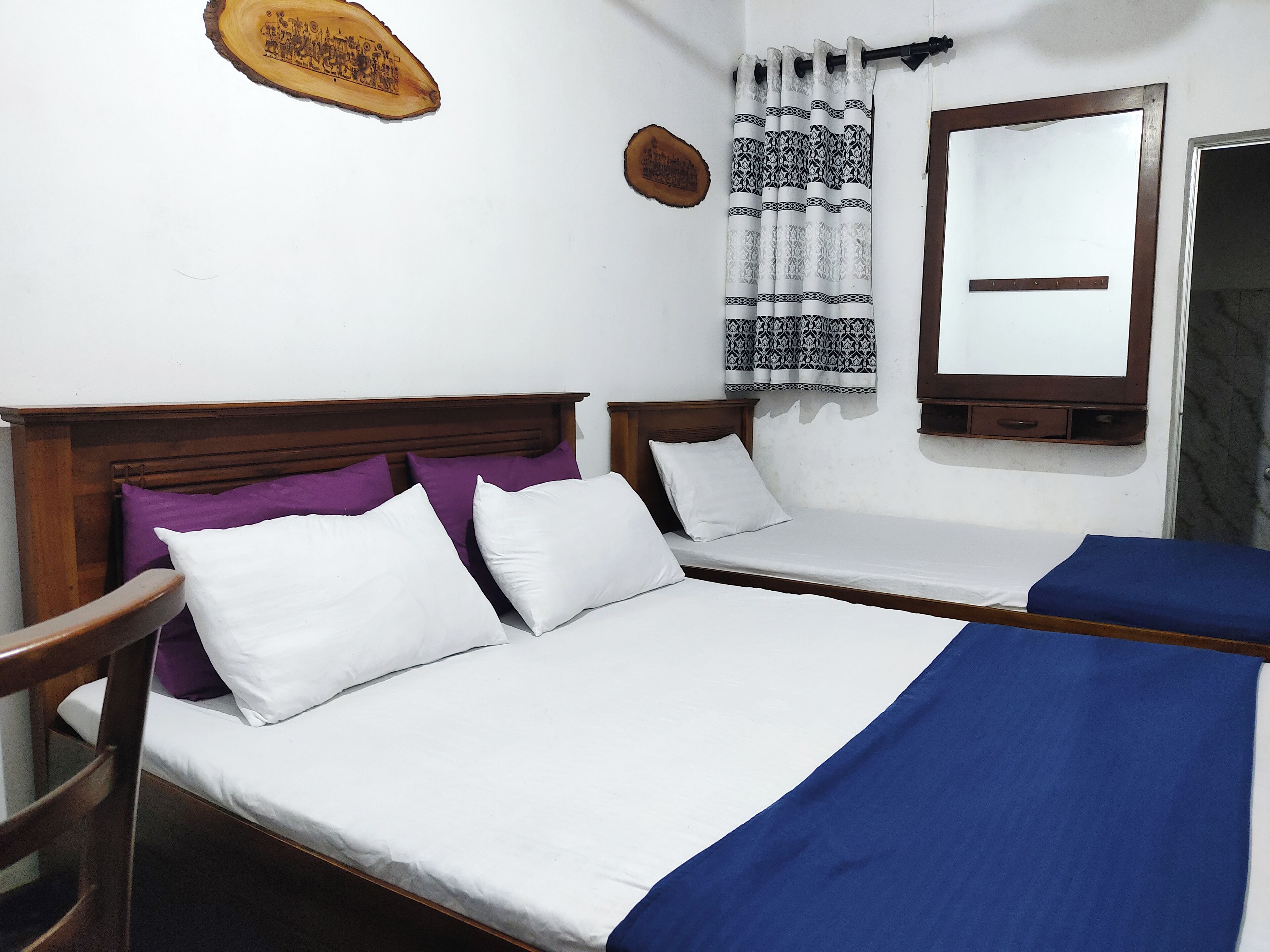 A double bed with white and purple pillows, a wooden headboard, and a blue blanket.